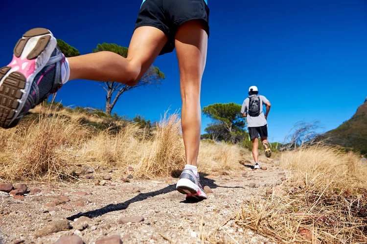 Two people run up a rocky hill