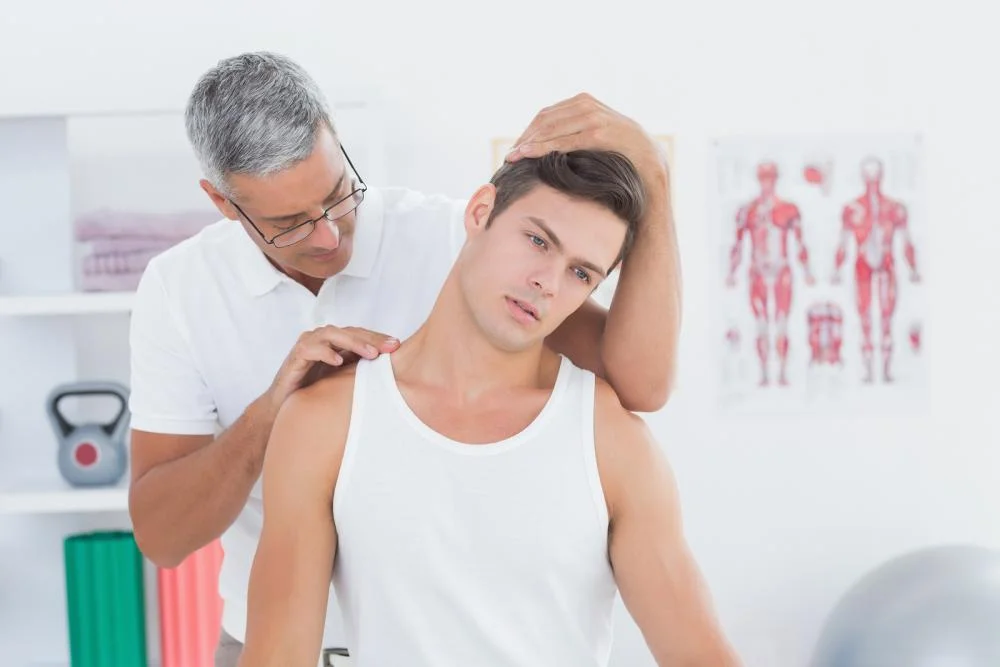 A chiropractor holds a patient's head while examining their neck