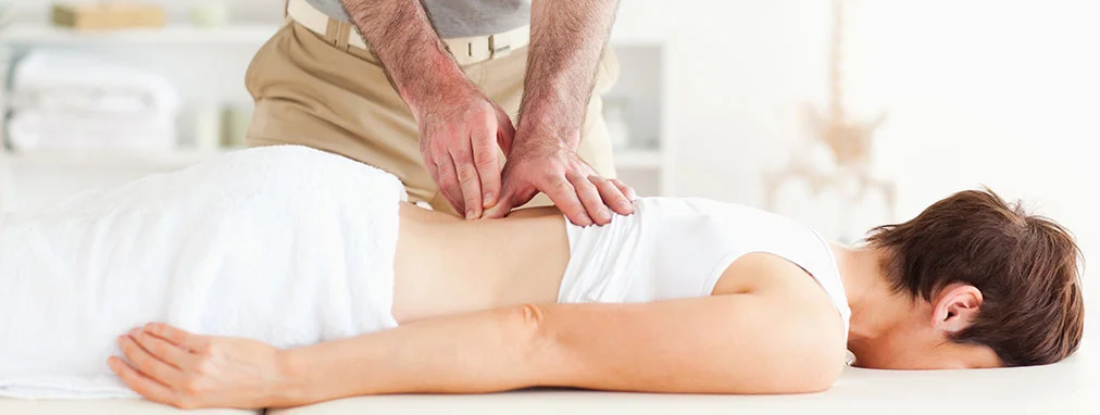 A chiropractor presses their hands into a patient's back