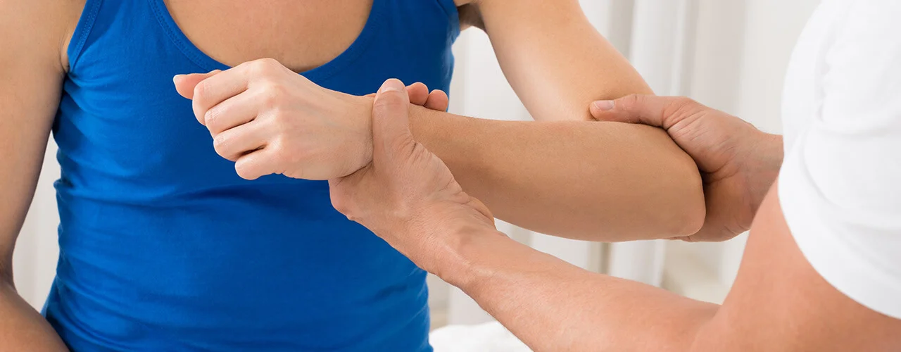 A chiropractor grips a patient's left arm