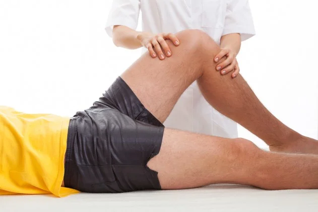 A chiropractor rests their hands on a patient's outstretched knee
