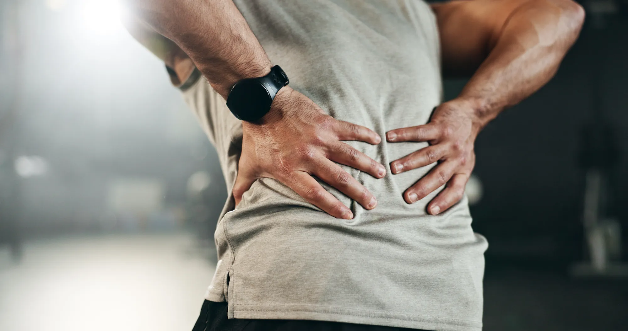 A man grabs his lower back with both hands.